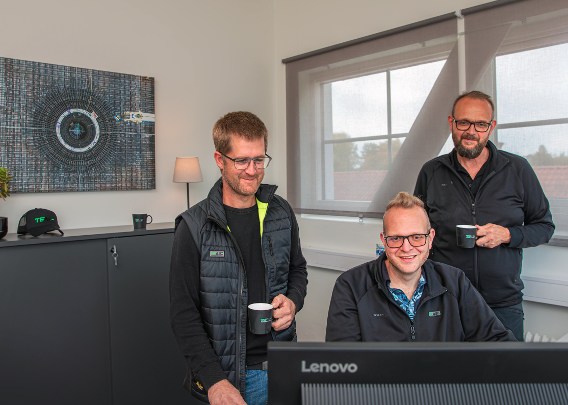 Tre TEAB-medarbetare samarbetar vid en Lenovo-dator på TEABs kontor.